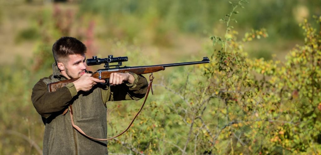 bearded-serious-hunter-spend-leisure-hunting-hunter-hold-rifle-hunting-is-brutal-masculine-hobby-hunting-trapping-seasons-man-brutal-unshaved-gamekeeper-nature-background-hunting-permit-min